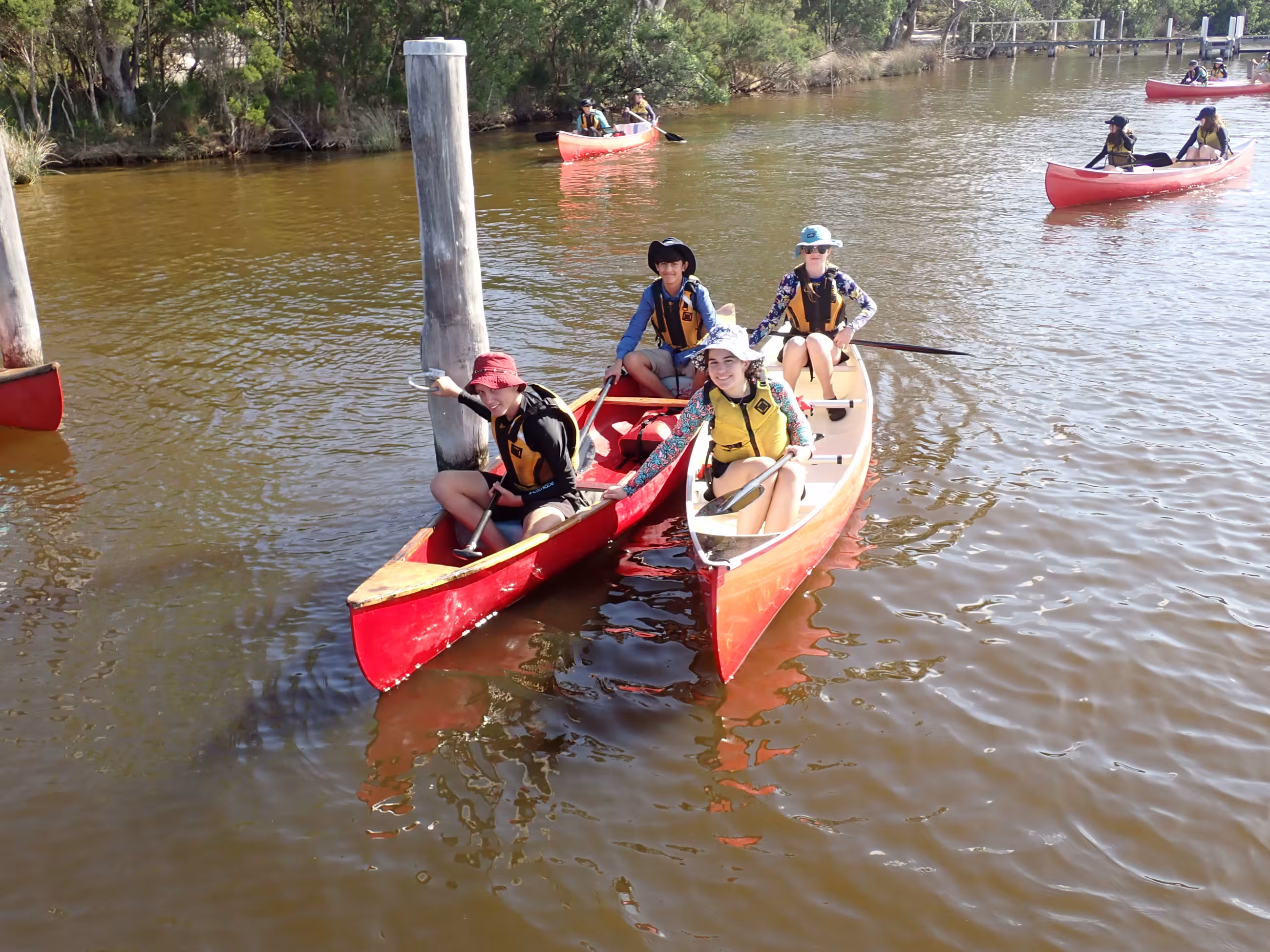 Smiling campers in two red canoes floating on a lake