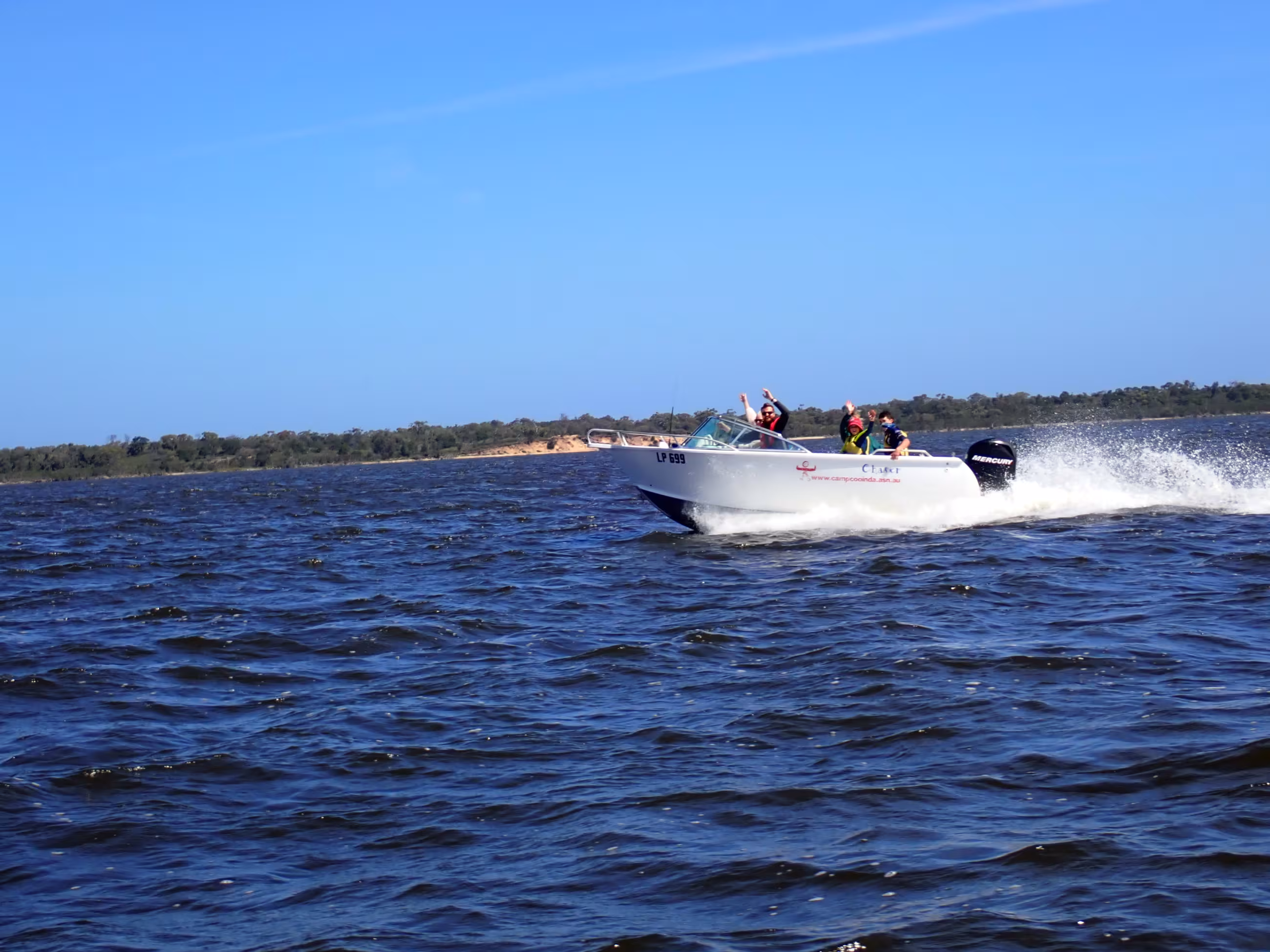 A speed boat travelling fast across a lake