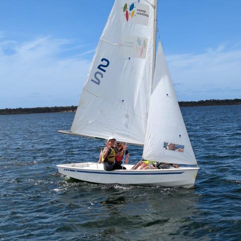 Young people waving from a sailing boat floating on a big lake
