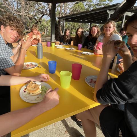 People sitting at a yellow table smiling at the camera